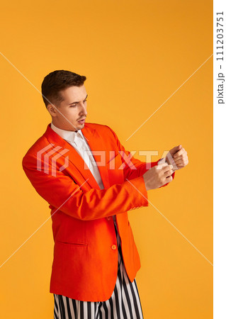 Cheerful funny young man in orange jacket and striped pants on yellow background. Cheerful funny young man in orange jacket and striped pants on yellow background. 111203751