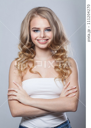 Smiling young woman with clean fresh skin and long curly hair looking at camera Smiling young woman with clean fresh skin and long curly hair looking at camera 111204270