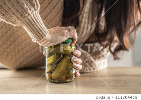 A woman tries to force open a jam jar with cucumbers A woman tries to force open a jam jar with cucumbers 111204458