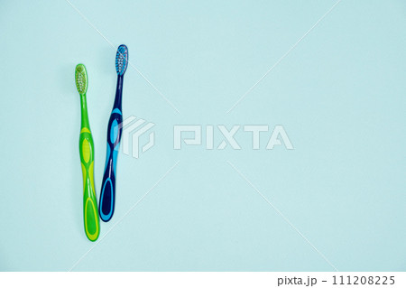 Two toothbrushes on a blue background, top view, space for text. Two toothbrushes on a blue background, top view, space for text. 111208225