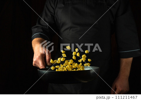 The cook prepares a healthy breakfast of pasta in a frying pan. Healthy vegetarian food and dishes recipe. Place on a dark background for the recipe The cook prepares a healthy breakfast of pasta in a frying pan. Healthy vegetarian food and dishes recipe. Place on a dark background for the recipe 111211467