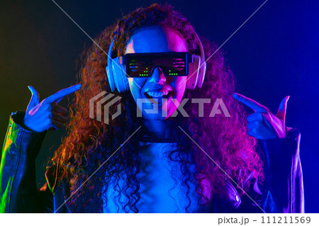 Positive woman listening music, enjoying with headphones, neon studio Positive woman listening music, enjoying with headphones, neon studio 111211569