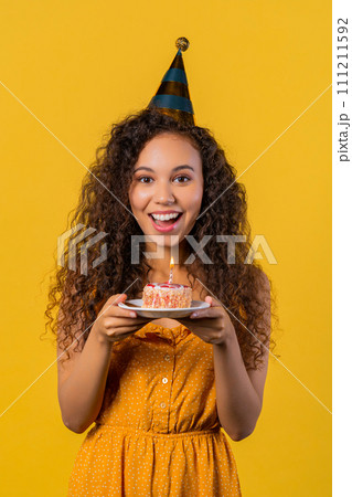 Happy birthday woman making wish - candle on cake. Girl smiling, celebrating. 111211592