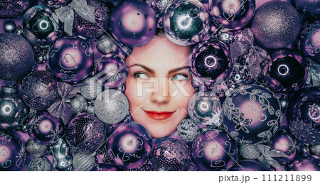 Happy woman face lights up with joy in violet Christmas tree toys balls. Holiday Happy woman face lights up with joy in violet Christmas tree toys balls. Holiday 111211899