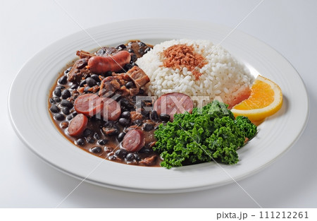 Traditional Brazilian dish feijoada with rice and kale in white plate on a white background 111212261