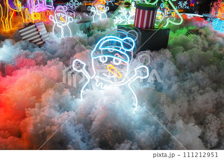 New Year and Christmas decorations, garlands, small architectural forms. Multi-colored light bulbs create festive atmosphere. A snowman 111212951