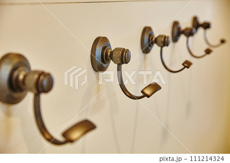 Minimalist Bronze Coat Hooks on Cream Wall, Eye-Level View Minimalist Bronze Coat Hooks on Cream Wall, Eye-Level View 111214324