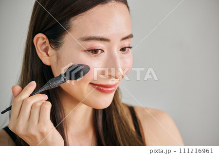 ファンデーションを塗るロングヘアの30代女性 111216961