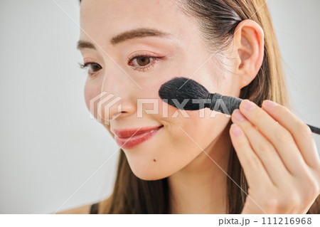 ファンデーションを塗るロングヘアの30代女性 111216968