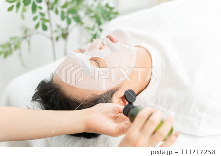 メンズフェイシャルエステでフェイスパック・保湿・トリートメントをする男性とエステティシャン 111217258