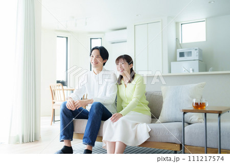 リビングでテレビを視聴する若い夫婦 リビングでテレビを視聴する若い夫婦 111217574