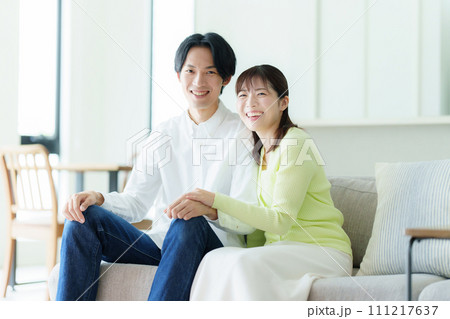 リビングでくつろぐ若い夫婦 リビングでくつろぐ若い夫婦 111217637