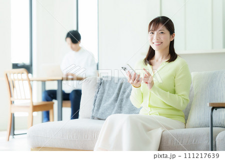 リビングでスマホを見るミドルの夫婦 111217639