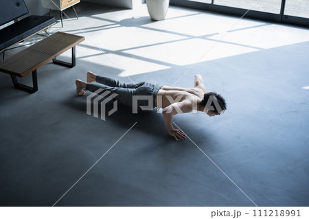 自宅リビングで腕立て伏せやプッシュアップの筋トレをする富裕層の男性　俯瞰	 111218991