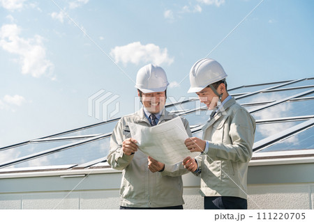 太陽光発電・ソーラーパネルの前に立つ電力会社・電気工事業者の作業着姿の技術者(クリーンエネルギー) 太陽光発電・ソーラーパネルの前に立つ電力会社・電気工事業者の作業着姿の技術者(クリーンエネルギー) 111220705