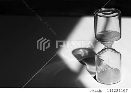 デスク上の砂時計　印象的な光と影とガラスの反射 111221167