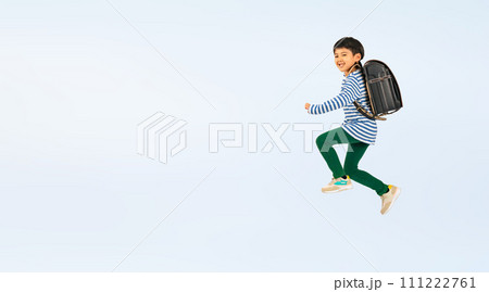 ランドセルを背負って笑顔でジャンプする小学生の男の子 111222761