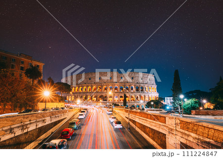 Rome, Italy. Bold Bright Dark Blue Night Starry Sky With Glowing Stars Above Colosseum Also Known As Flavian Amphitheatre In Evening Or Night Time. Travel To Italy 111224847