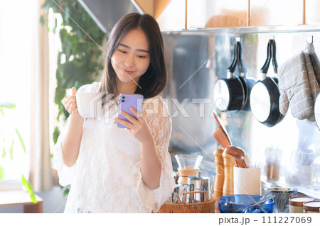 キッチンでコーヒーを飲む大学生の女性 111227069