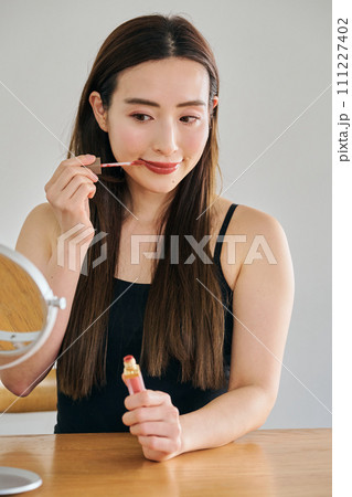 リップグロスを塗るロングヘアの30代女性 111227402