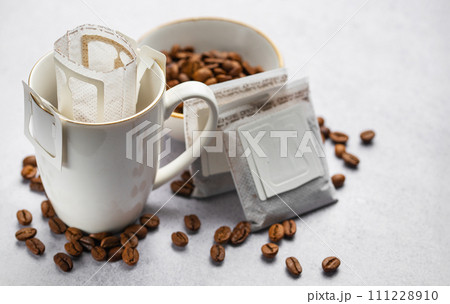 Drip coffee bag with ground coffee in cup Drip coffee bag with ground coffee in cup 111228910