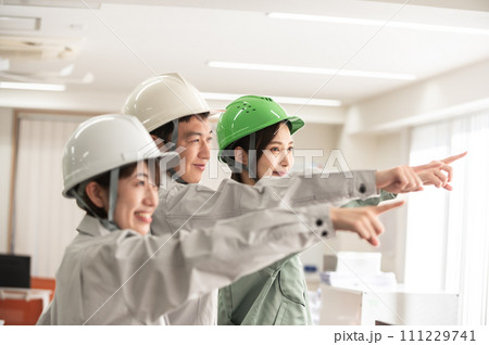 ヘルメットを着用して指さし呼称する男女3人のエンジニア 111229741