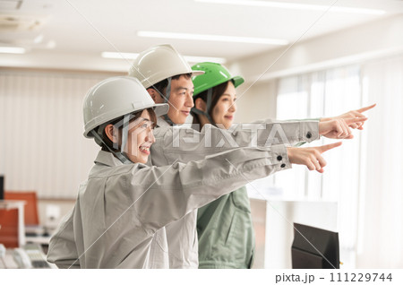 ヘルメットを着用して指さし呼称する男女3人のエンジニア 111229744