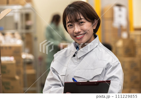 物流倉庫で働く作業着姿の女性スタッフ 111229855