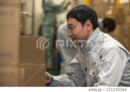 物流倉庫で検品作業をする作業着姿の男性 111230164