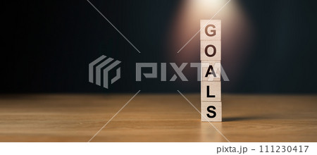 Wooden blocks stacked vertically spelling GOALS with spotlight effect, symbolizing focus on setting personal and business objectives. Wooden blocks stacked vertically spelling GOALS with spotlight effect, symbolizing focus on setting personal and business objectives. 111230417