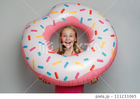 Excited child girl with pink rubber inflatable ring swimming pool float standing  111231065