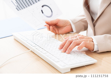パソコンでデスクワークをするスーツ姿のミドル女性の手元 111231758