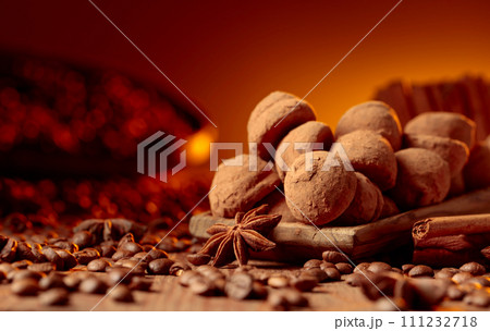 Chocolate truffles with cinnamon, anise, and coffee beans on a wooden table. Chocolate truffles with cinnamon, anise, and coffee beans on a wooden table. 111232718