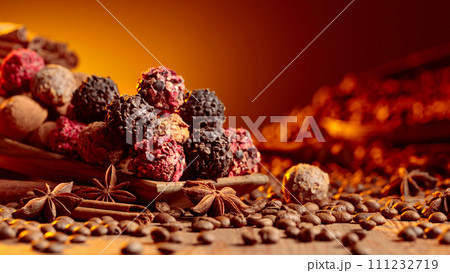 Chocolate truffles with cinnamon, anise, and coffee beans on a wooden table. Chocolate truffles with cinnamon, anise, and coffee beans on a wooden table. 111232719