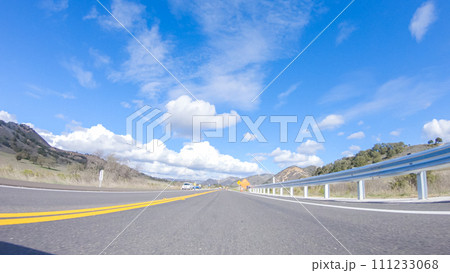 Vehicle is cruising along the Cuyama Highway under the bright sun. The surrounding landscape is illuminated by the radiant sunshine, creating a picturesque and inviting scene as the car travels Vehicle is cruising along the Cuyama Highway under the bright sun. The surrounding landscape is illuminated by the radiant sunshine, creating a picturesque and inviting scene as the car travels 111233068