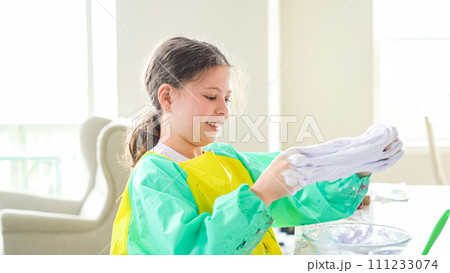 In a modern kitchen, a homeschooled girl is engrossed in creating homemade slime, a fun and educational hands-on project that enhances her creativity and problem-solving skills. In a modern kitchen, a homeschooled girl is engrossed in creating homemade slime, a fun and educational hands-on project that enhances her creativity and problem-solving skills. 111233074