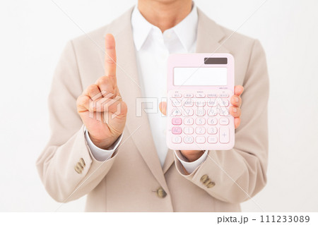 ピンク色の電卓を持って人差し指を立てるベージュのスーツを着たミドル女性のビジネスウーマン 111233089