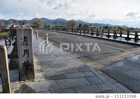 日本の春の京都 嵐山周辺の街並み 観光名所の渡月橋と木造の看板 美しい桜と新緑 日本の春の京都 嵐山周辺の街並み 観光名所の渡月橋と木造の看板 美しい桜と新緑 111233386