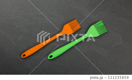 Two silicone culinary brushes on black slate board 111235859