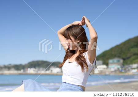 晴れの日の砂浜にたたずむ女性 111236310