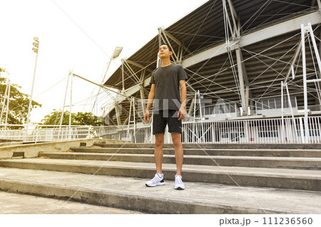 Young athlete asian man running in front of the stadium. The man trains outdoors. Preparing for the marathon. Young athlete asian man running in front of the stadium. The man trains outdoors. Preparing for the marathon. 111236560