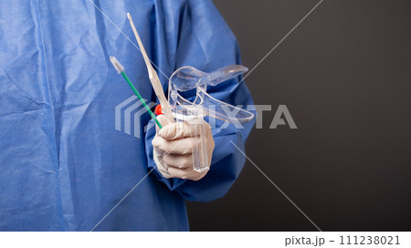 A female doctor is a gynecologist in a blue robe. Gynecological accessories, venus mirror, brush. Grey background, empty space for text. 111238021