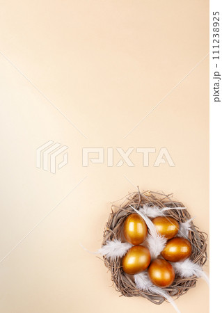 Empty space for text, a banner of happy Easter. Painted golden eggs, white feathers. copy space flat lay top view Vertical nest with eggs 111238925