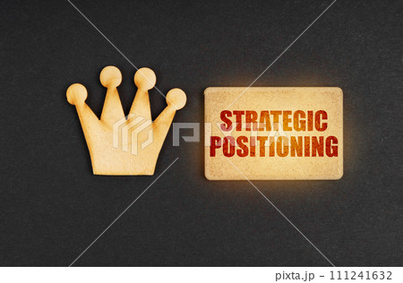 On a black background there is a wooden crown of the leader and a sign with the inscription - Strategic Positioning On a black background there is a wooden crown of the leader and a sign with the inscription - Strategic Positioning 111241632