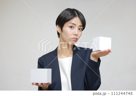 四角の箱を2つ持ち迷って困っている女性_1 四角の箱を2つ持ち迷って困っている女性_1 111244748