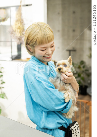 ドッグサロンでヨークシャーテリアを抱くショートヘアの女性 111245165