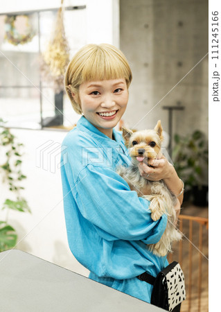 ドッグサロンでヨークシャーテリアを抱くショートヘアの女性 111245166