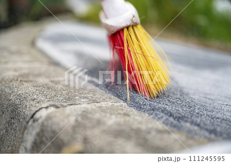 Broom filling freshly layed tile gaps with special filler sand 111245595