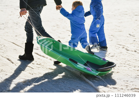 A father with children sledding in the snow 111246039
