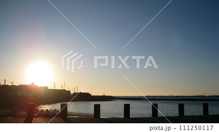 夕日で照らされた海と海岸沿いの住宅地 111250117